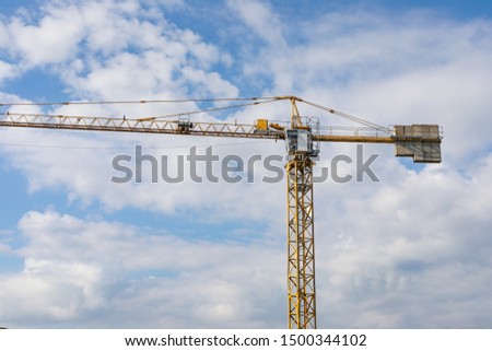 Picture of a construction crane against blue, cloudy sky