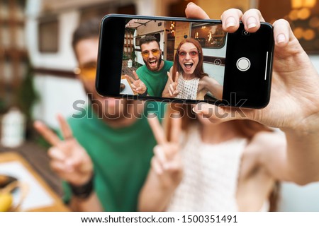 Close up of a couple sitting at the trailer outdoors and taking a selfie with outstretched hand holding mobile phone