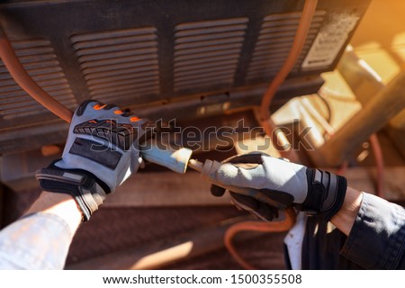 Construction worker wearing a heavy duty hand safety protection glove while inspecting and connecting welding lead cable prior performing weld construction site Sydney, Australia   