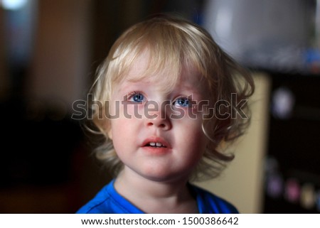 Portrait of a crying boy. Kid with sad expression looking TV. Emotions on the face of baby.