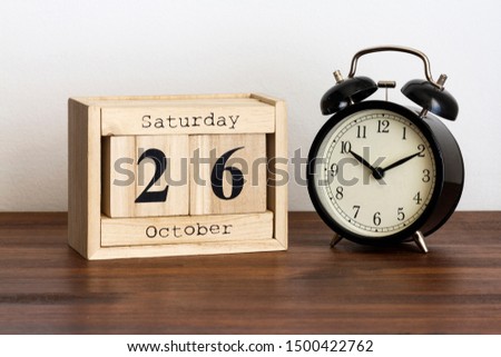 Wood calendar with date and old clock. Saturday 26 October