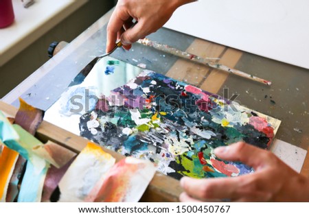 Paint palette. Real work studio of the painter. Man is creating picture. Artist concept. Creative atmosphere.