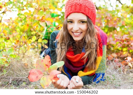 Attractive autumn woman in hat and warm scarf posing outside in colorful fall forest