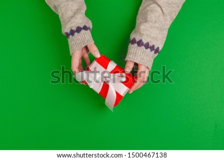 Woman hands holding gift box on green background