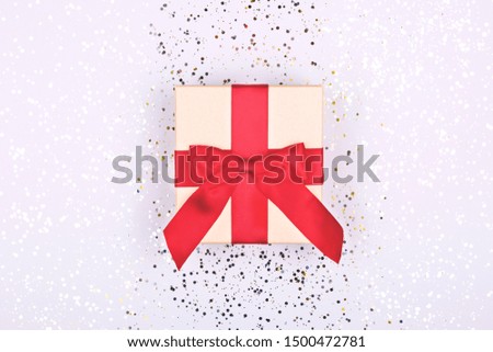Gift box with red ribbon on sparkle glitter background. Christmas or New Year present concept.