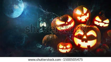 Halloween pumpkin head jack lantern with burning candles in scary deep night forest
