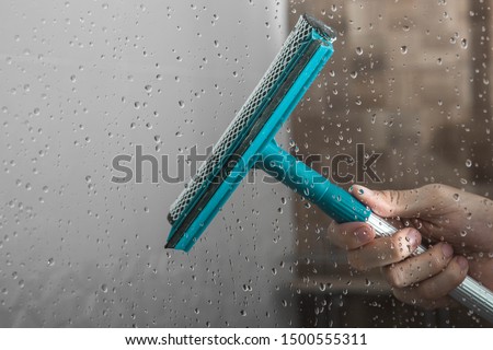 close up cleaning shower glass door with squeegee Royalty-Free Stock Photo #1500555311