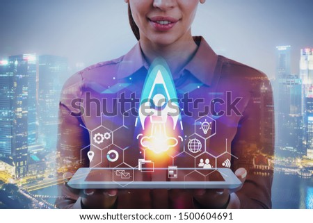 Smiling businesswoman with tablet standing in night city with double exposure of startup interface. Concept of new project launch. Toned image Royalty-Free Stock Photo #1500604691