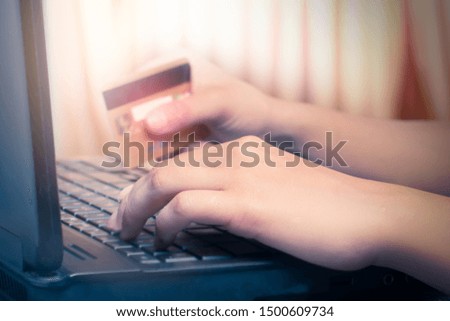 A woman holds a credit card while shopping online on a laptop