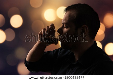 A young man drinks an alcoholic drink on a blurred background