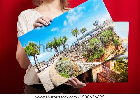 Canvas prints. A woman holding two photographs with gallery wrap on red background. Landscape photo printed on glossy synthetic canvas and stretched on wooden stretcher bar