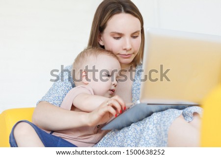 portrait of cheerful lovely mother gently and carefully hugs her children and together with kid looks at children's tales or cartoons on laptop. Mom calms the child with gadgets. Parenthood