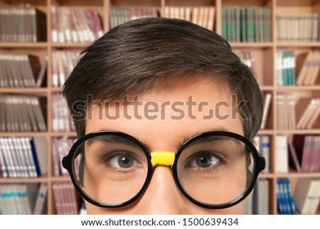 A young man with glasses on the background of the library