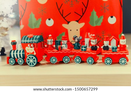 Christmas wooden train toys with snowman and friends and gift box in background.