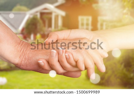 Hands of the old man and a young woman on blurred your house