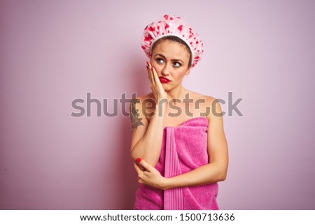 Young beautiful woman wearing towel and bath hat after shower over pink isolated background thinking looking tired and bored with depression problems with crossed arms.