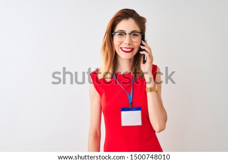Redhead businesswoman wearing id card talking on smartphone over isolated white background with a happy face standing and smiling with a confident smile showing teeth