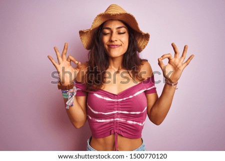 Young beautiful woman wearing t-shirt and summer hat over isolated pink background relax and smiling with eyes closed doing meditation gesture with fingers. Yoga concept.