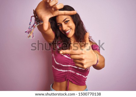 Young beautiful woman wearing casual t-shirt standing over isolated pink background smiling making frame with hands and fingers with happy face. Creativity and photography concept.