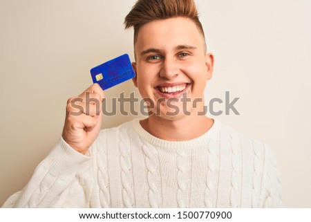 Young handsome man holding credit card over isolated white background with a happy face standing and smiling with a confident smile showing teeth