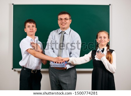 Portrait of a teacher and pupil, posing at blackboard background - back to school and education concept