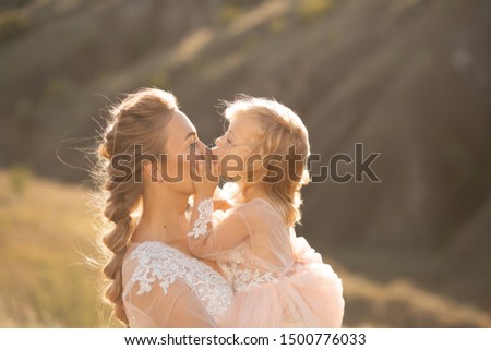 Portrait of a beautiful young mom holds her beloved daughter in her arms. Parental love, little princess.