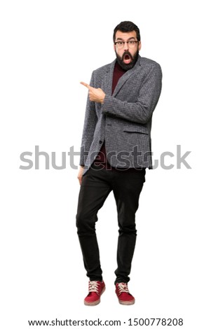 Handsome man with glasses surprised and pointing side over isolated white background