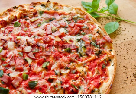 Close up Rustic pizza with ham , mozzarella ,  spring onion , onions and tomato sauce. Served on wooden board garnish with basil leaves and oregano. Angle view and selective focus