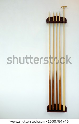 billiard cue sticks, Cue snooker  hang on white wall, Billiard cues on the rack, Wooden cues for table game, Cue stick shaft tapering with fiberglass. Maple wooden sticks for billiard playing Royalty-Free Stock Photo #1500784946
