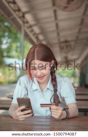 Portrait Asian girl use smart phone and credit card to shoping online, Thailand student
