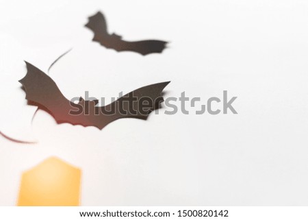 Halloween decorations with paper bats, candles and ghosts on white background. Halloween and decoration concept. Lens flare effect. Flat lay, top view, copy space