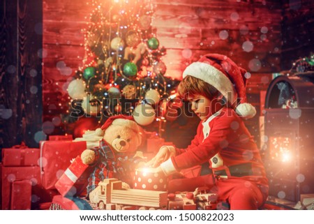 Christmas kids story concept. First memory of childhood. Christmas miracle and new year feelings. A little boy in warm clothes sitting and playing with wooden toys gift. Open-ended Games