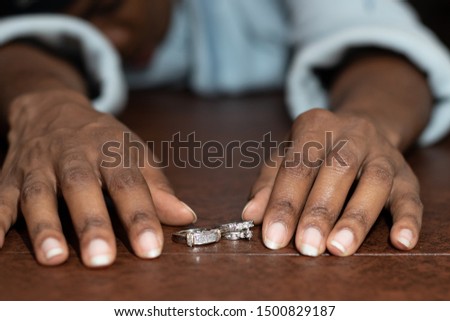 African American Woman sadly looking at wedding rings