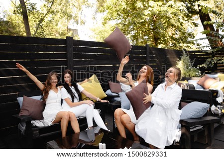 Group of friends in white preparing to pose for a photoshoot in a cafe garden in the Summer morning