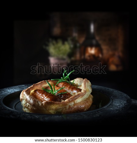 Traditional British cuisine of baked pork sausages in batter mix colloquially termed as Toad In The Hole. Typically served with green vegetables and roast potatoes. Copy space.