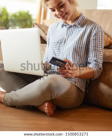 Beautiful young woman using credit card and laptop for online shopping