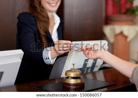 smiling female receptionist passing card to guest