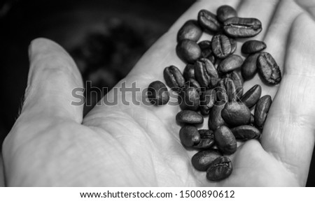 Close up black and white photo of coffee beans in a man's hand. 