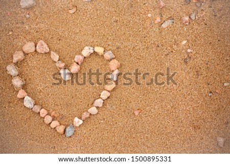 Heart on the beach. Heart of stones on a golden beach. Symbol of love, photography background or blank for greeting card.  Valentines day. Concept with heart on the theme of holidays and travel. 