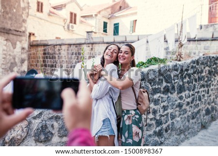 Two female friends photographed by friend on smartphone