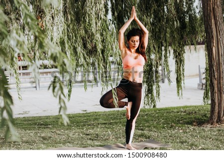 Latin woman does yoga exercises in a park in Madrid. Balance and concentration.