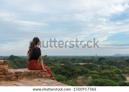 Wide angle picture of young woman looking the archeological park from the rooftop of old buddhist temple in Bagan, Myanmar
