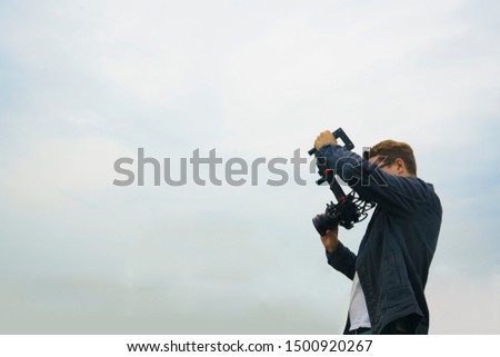 video camera, cameraman on green grass field background.photographer records the sunset in the background of meadow.Professional videographer on adventure vacation shooting camera 