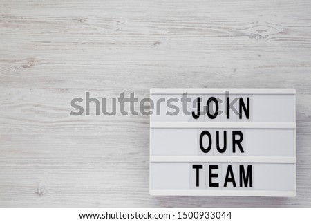 Top view, 'Join our team' words on a modern board on a white wooden surface. Overhead, from above, flat lay. Copy space.