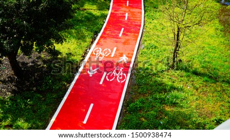 Bike path seen from above with white paint markings on the red surface