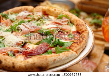 Pizza with prosciutto ham, aruglua and grated parmesan, close-up