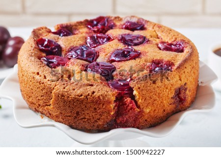 close-up of  plum torte on a white platter, horizontal view from above