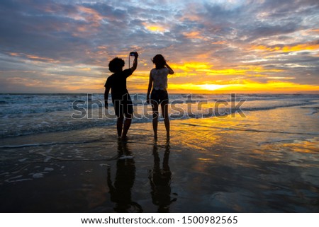 Black silhouettes of couple girl against the sunset on the sea.