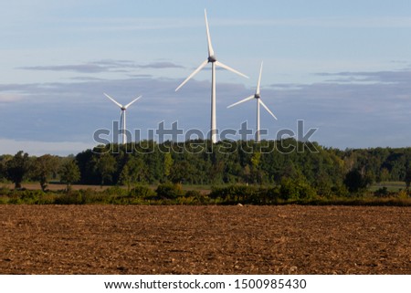 Clean energy wind turbines standing over a recently harvested potato field near Montreal, Canada.