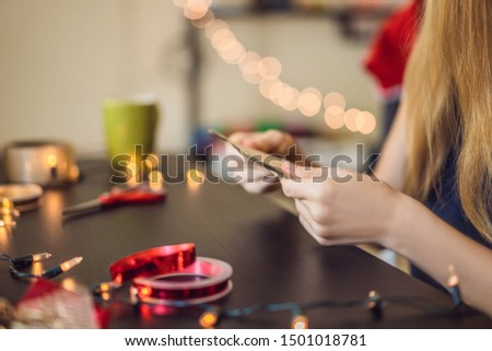 Young woman is packing presents. Present wrapped in craft paper with a red and gold ribbon for christmas, birthday, mother's day or valentine